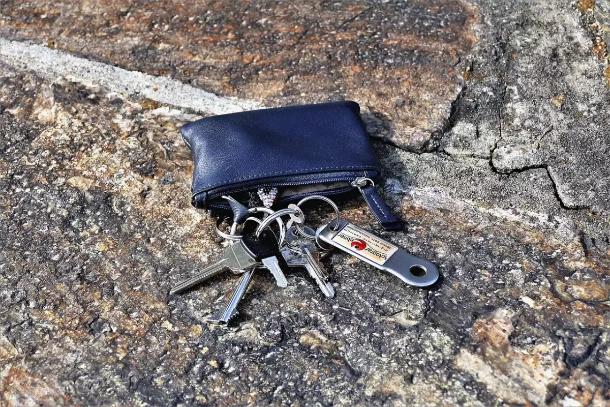 Verlorener Schlüsselbund mit blauem Etui auf dem Asphalt am Straßenrand